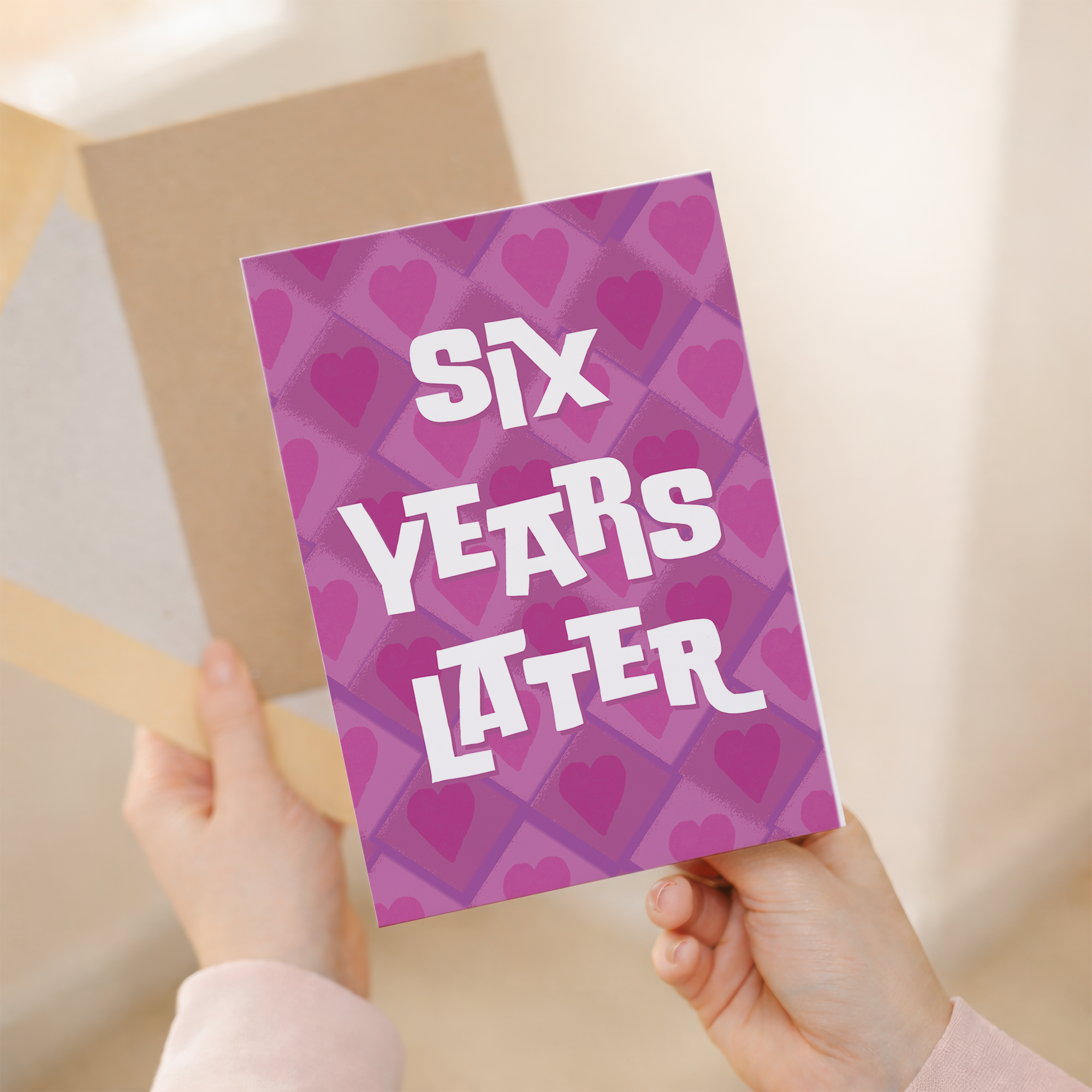 A simple and modern 5x7 inch 6th wedding anniversary card featuring elegant pink, white, and purple design elements on sustainable recycled cardstock, paired with a brown Kraft envelope.