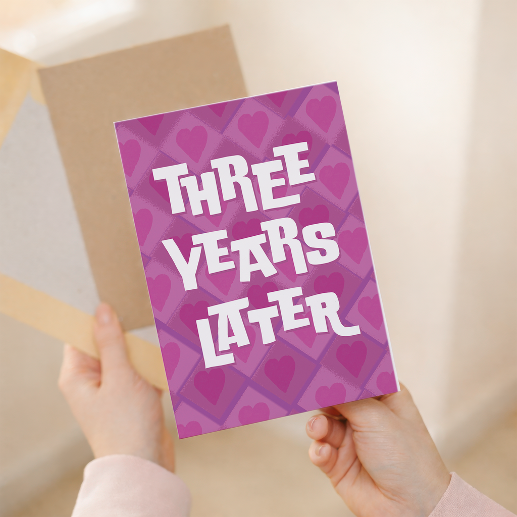 Minimalist 3rd wedding anniversary greeting card featuring the number three in a clean, modern font with pink and purple floral accents on white recycled cardstock, accompanied by a brown Kraft envelope.