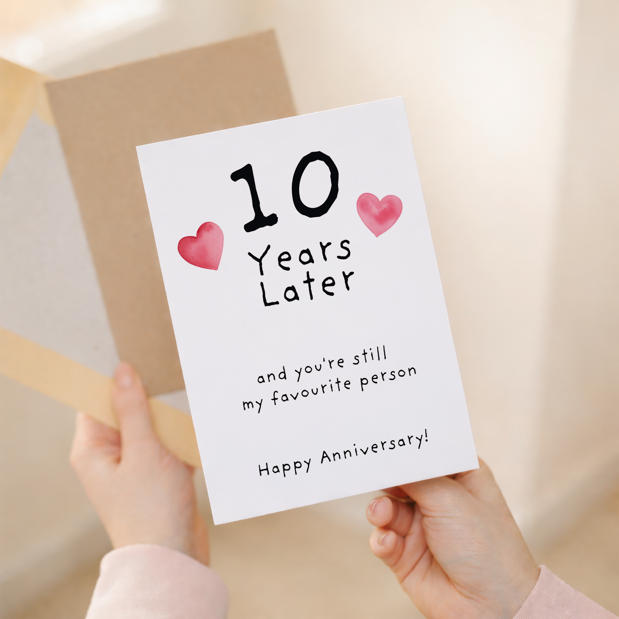Charming 10th wedding anniversary greeting card crafted from sustainable recycled cardstock with natural specks and dots, paired with a brown kraft envelope.