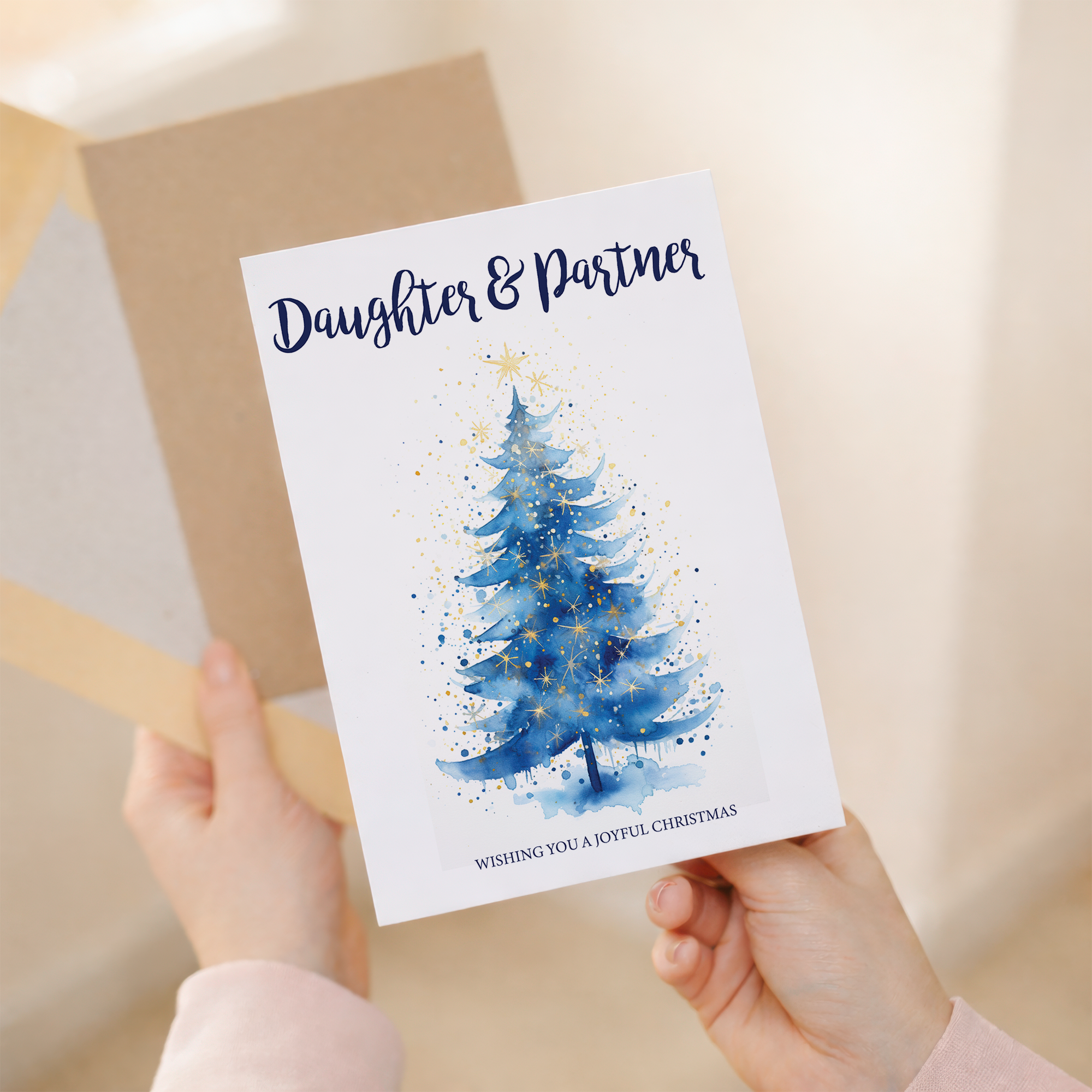 Vertical 5x7 greeting card featuring a minimalist illustration of a decorated Christmas tree. The card is displayed on a brown kraft envelope.