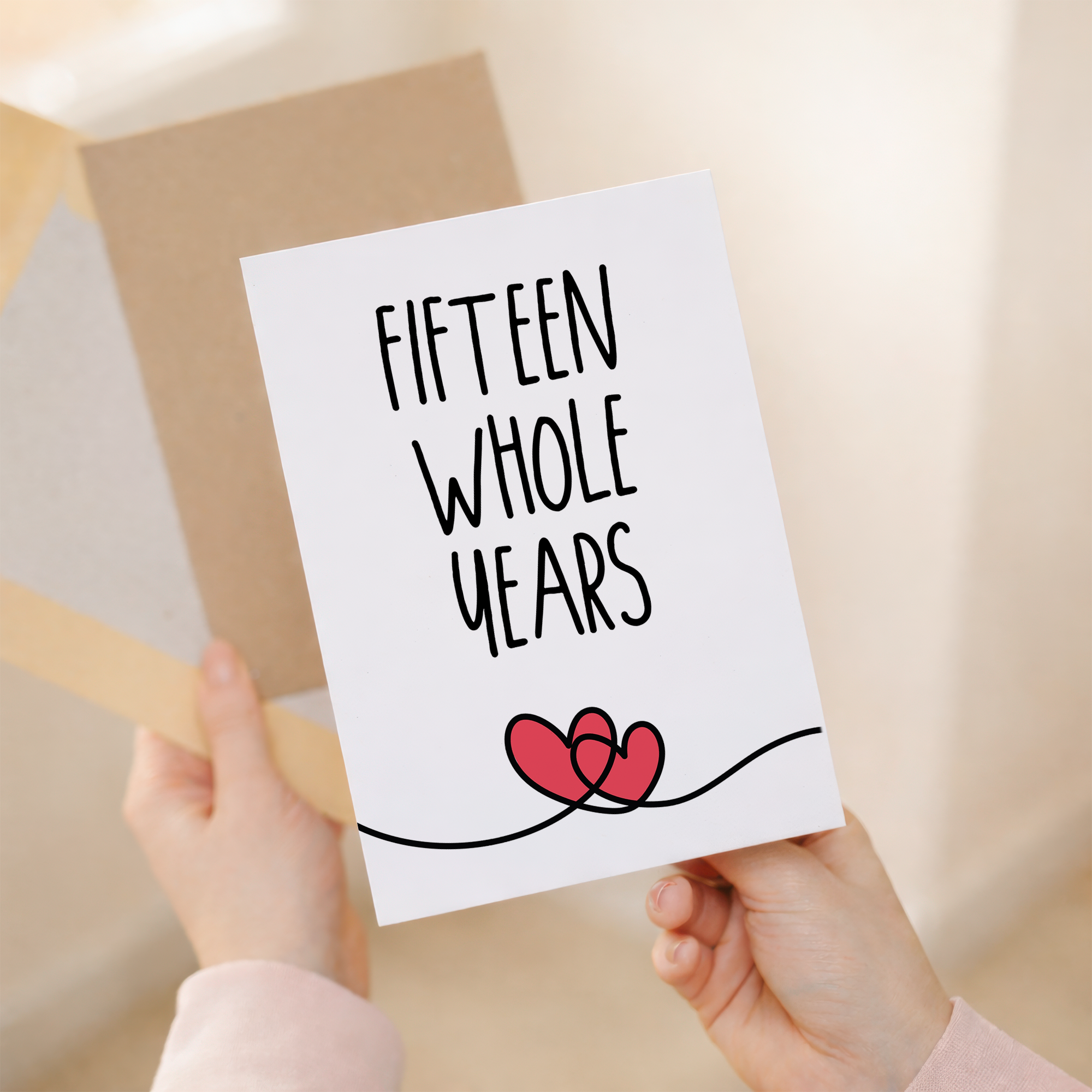 Elegant 15th anniversary greeting card featuring a minimalist heart design on sustainable recycled cardstock, accompanied by a rustic brown Kraft envelope.