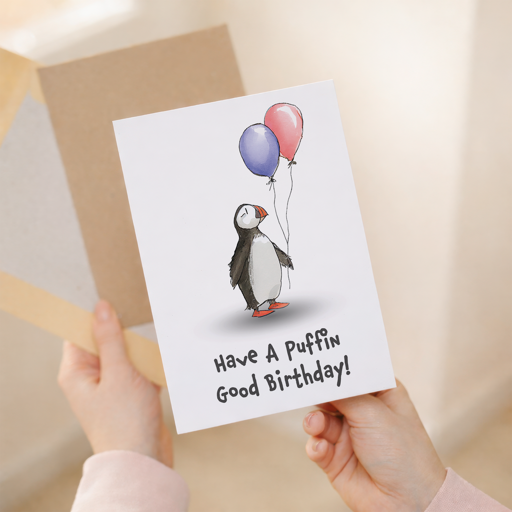 Cute illustrated birthday card for children featuring a happy puffin bird with a colorful party hat on a plain background.