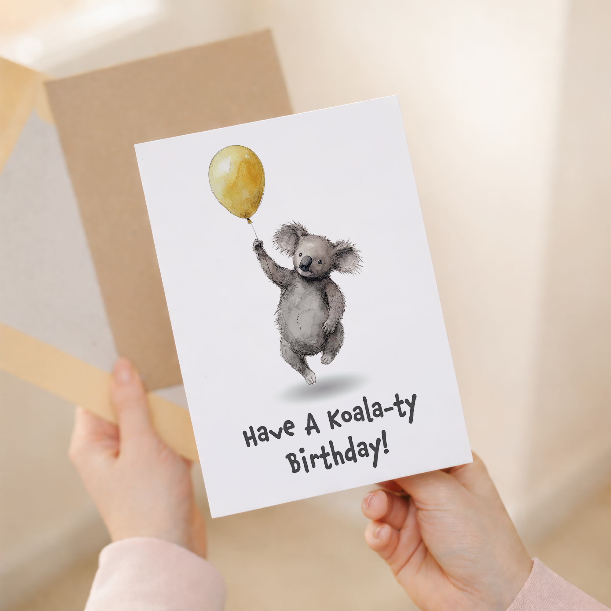 A cute koala illustration on a birthday card for children, featuring a soft gray koala with large ears and a gentle expression.