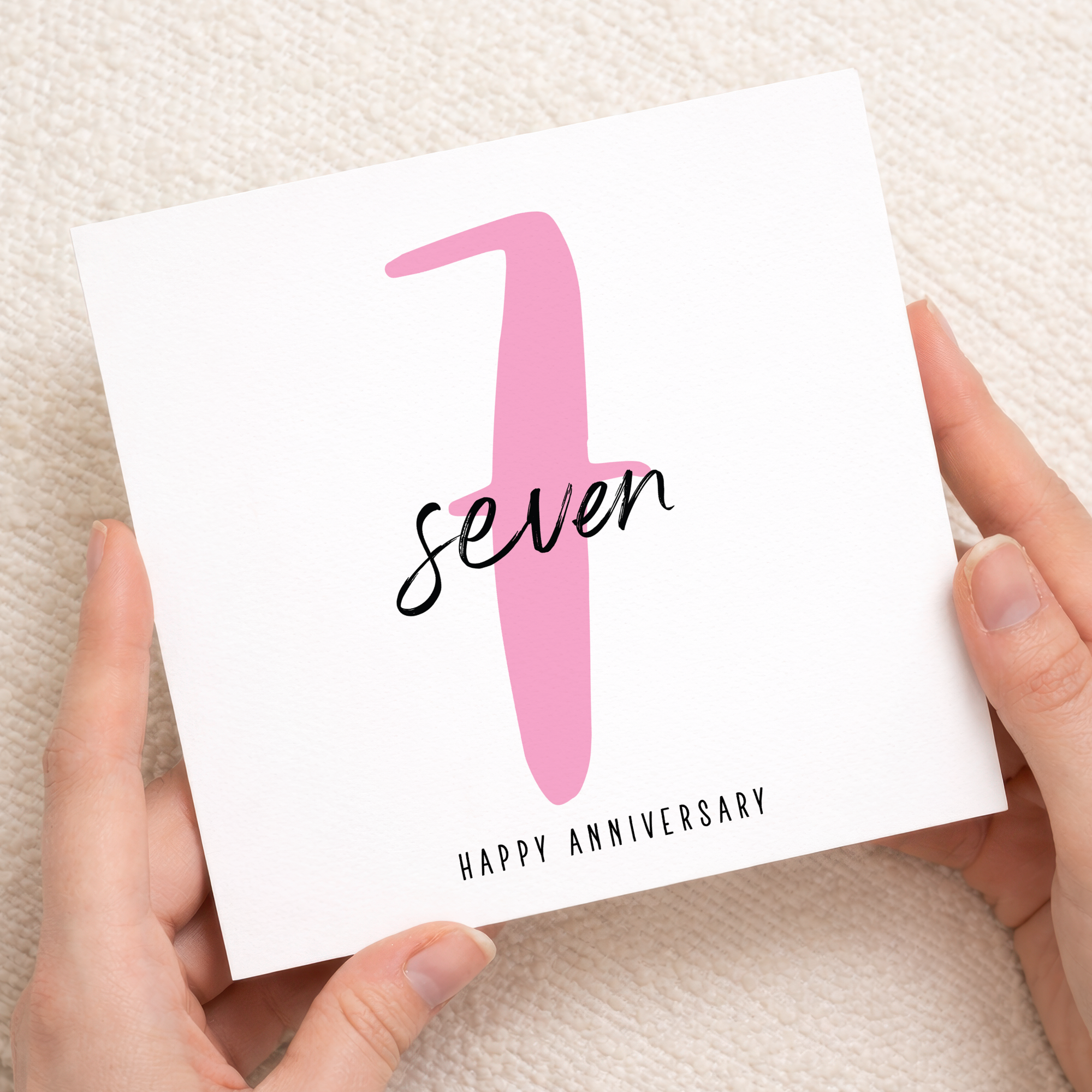 A modern 7th wedding anniversary greeting card featuring a pink and white design on a white background.