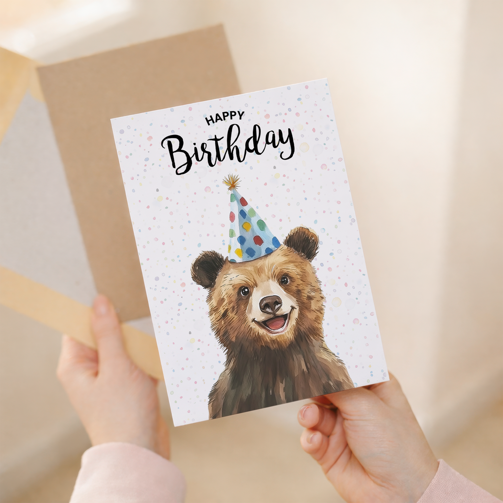 A charming watercolor illustration of a brown bear on a white birthday greeting card.