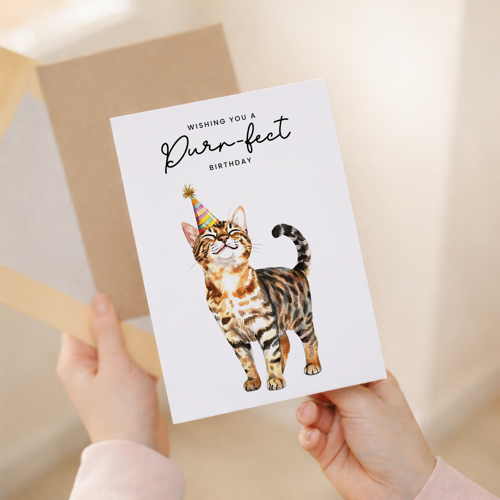 Cute Bengal cat wearing a colorful party hat on a vertical birthday greeting card.