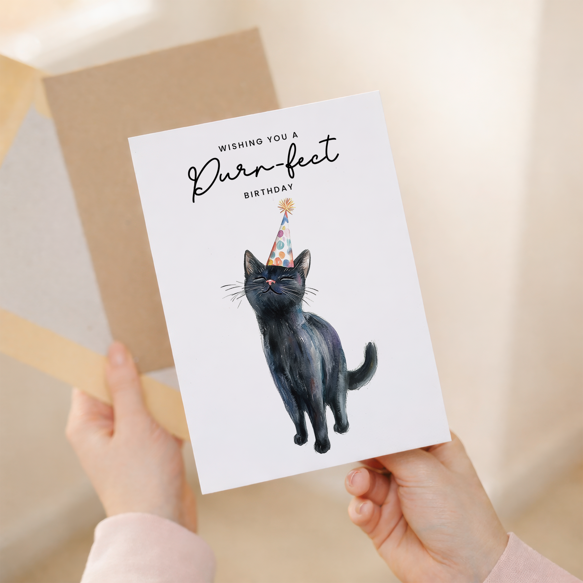 A cute illustration of a black cat wearing a colorful party hat on a white birthday greeting card.