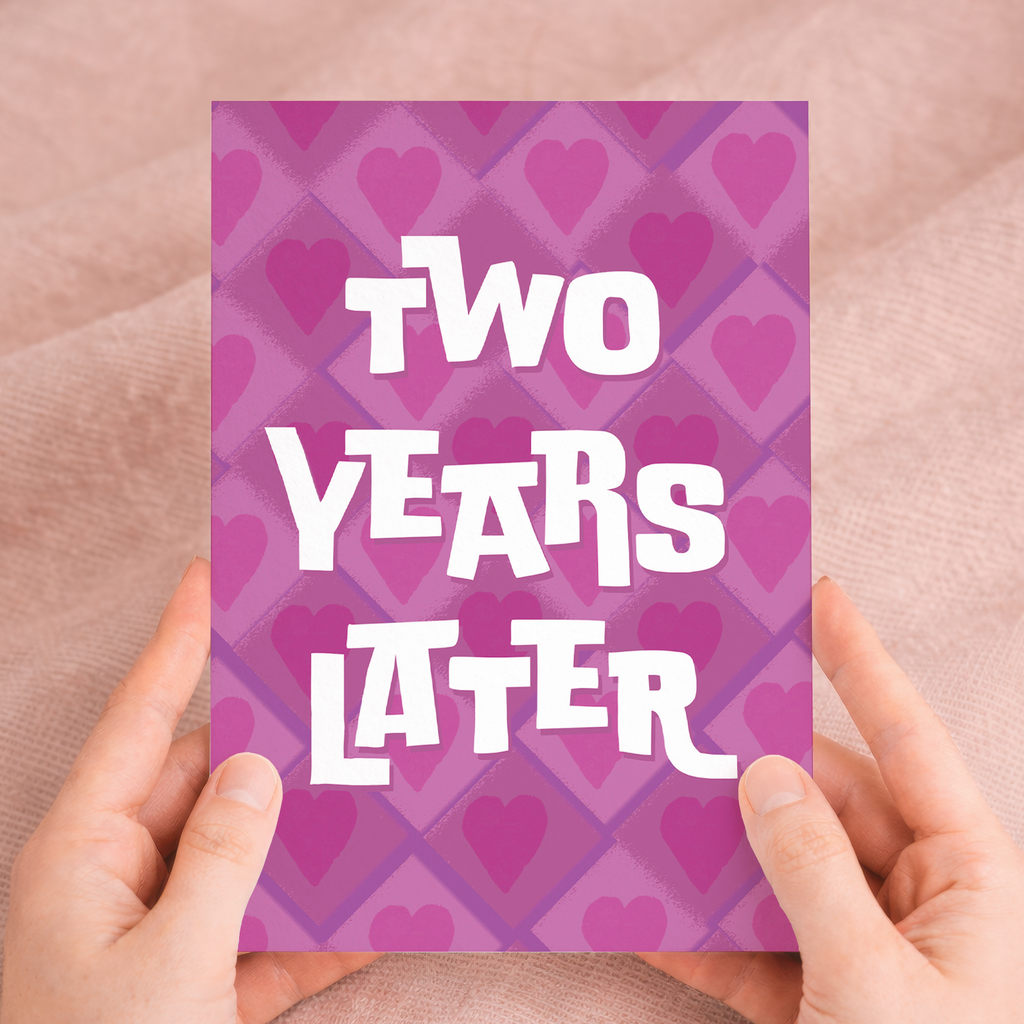 A simple and modern 2nd wedding anniversary greeting card featuring a large number 2 in pink, white, and purple floral patterns on eco-friendly cardstock, paired with a brown Kraft envelope.