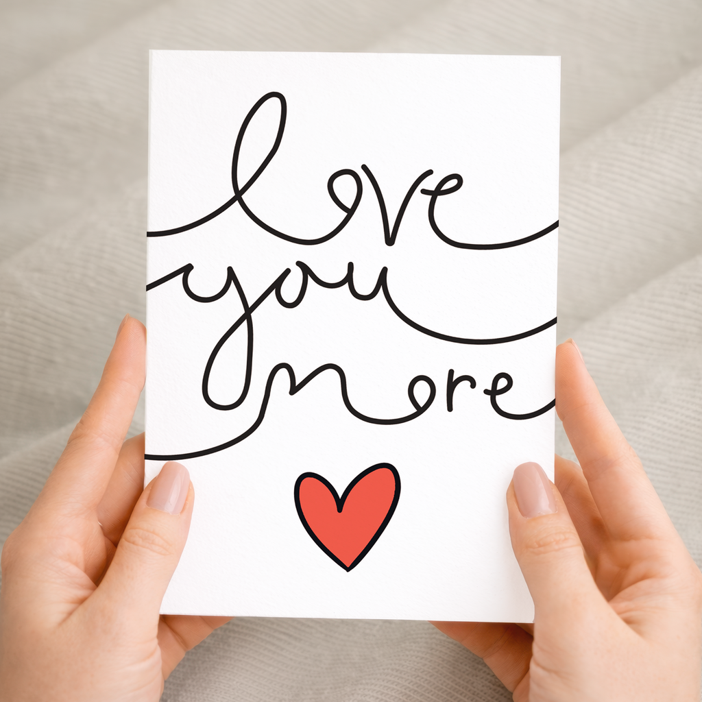Minimalist anniversary or Valentine's Day greeting card featuring the text Love You More in a clean, modern font, crafted on sustainable recycled cardstock and paired with a brown Kraft envelope.