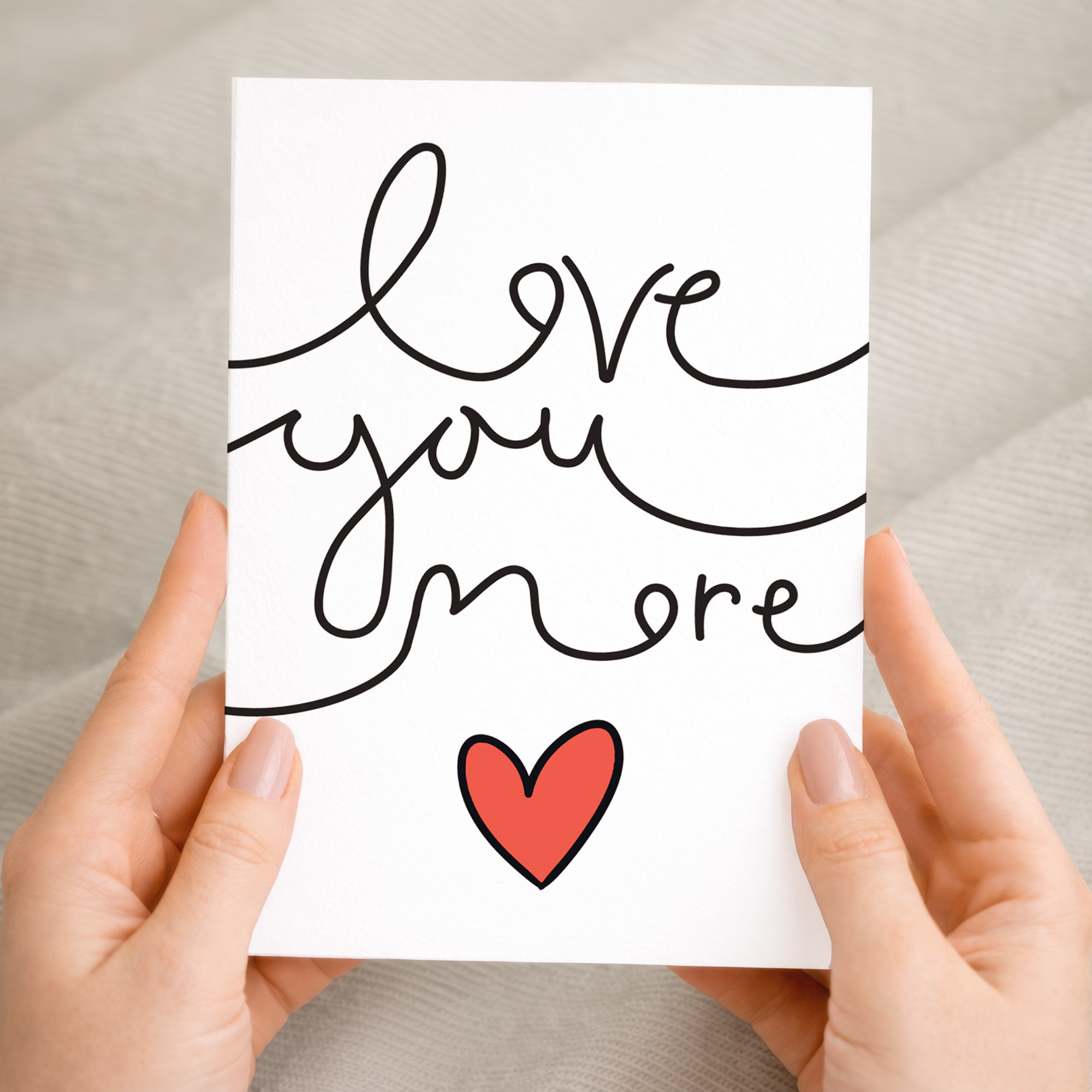 Minimalist anniversary or Valentine's Day greeting card featuring the text Love You More in a clean, modern font, crafted on sustainable recycled cardstock and paired with a brown Kraft envelope.