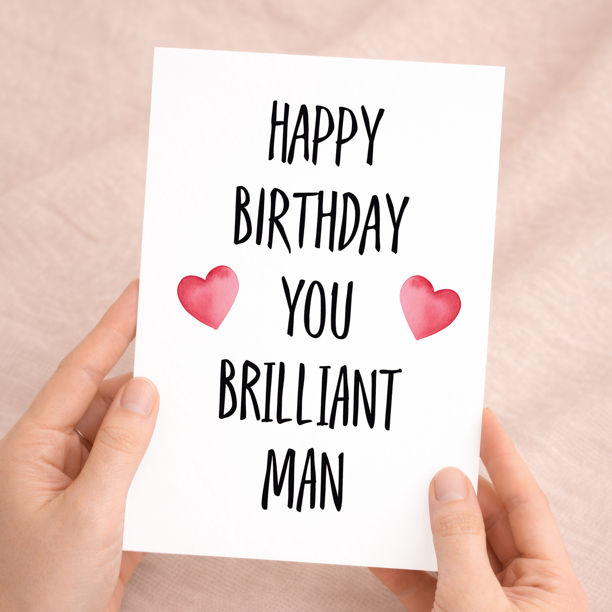 Minimalist birthday greeting card featuring the text "To a Brilliant Man" in bold, dark typography on a clean white background, accompanied by a rustic brown Kraft envelope.