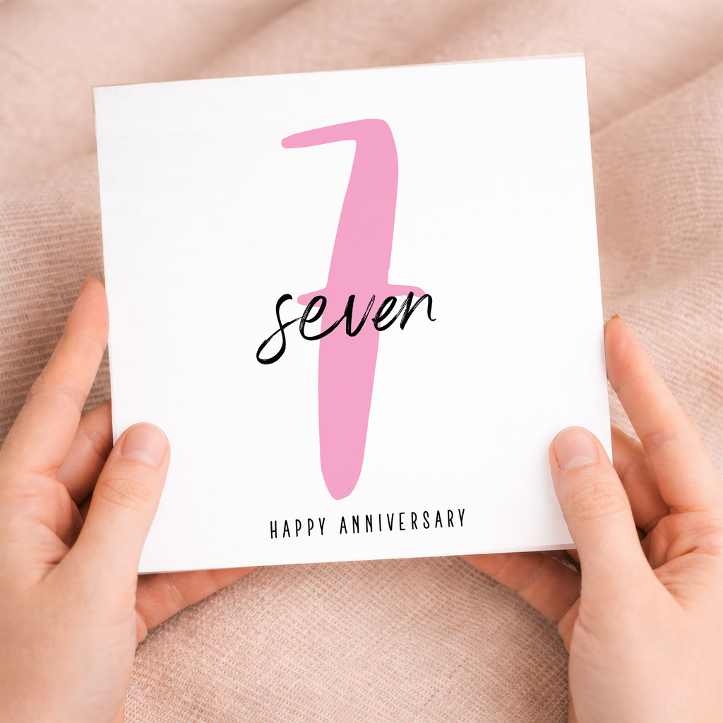 A modern 7th wedding anniversary greeting card featuring a pink and white design on a white background.