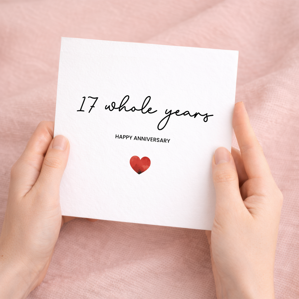 A simple 17th anniversary greeting card featuring a small red love heart in the center, accompanied by a brown kraft envelope on a white background.