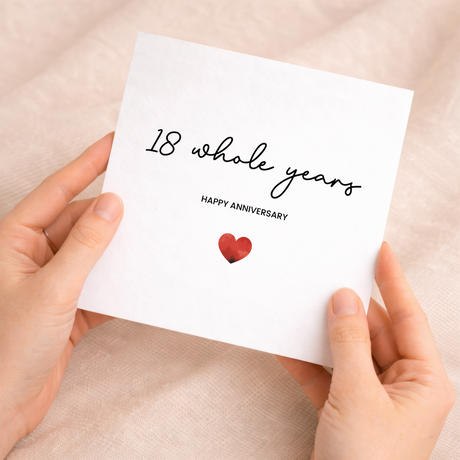 A simple 18th anniversary card featuring a small red heart in the center of a white background, with modern black text above and below the heart.