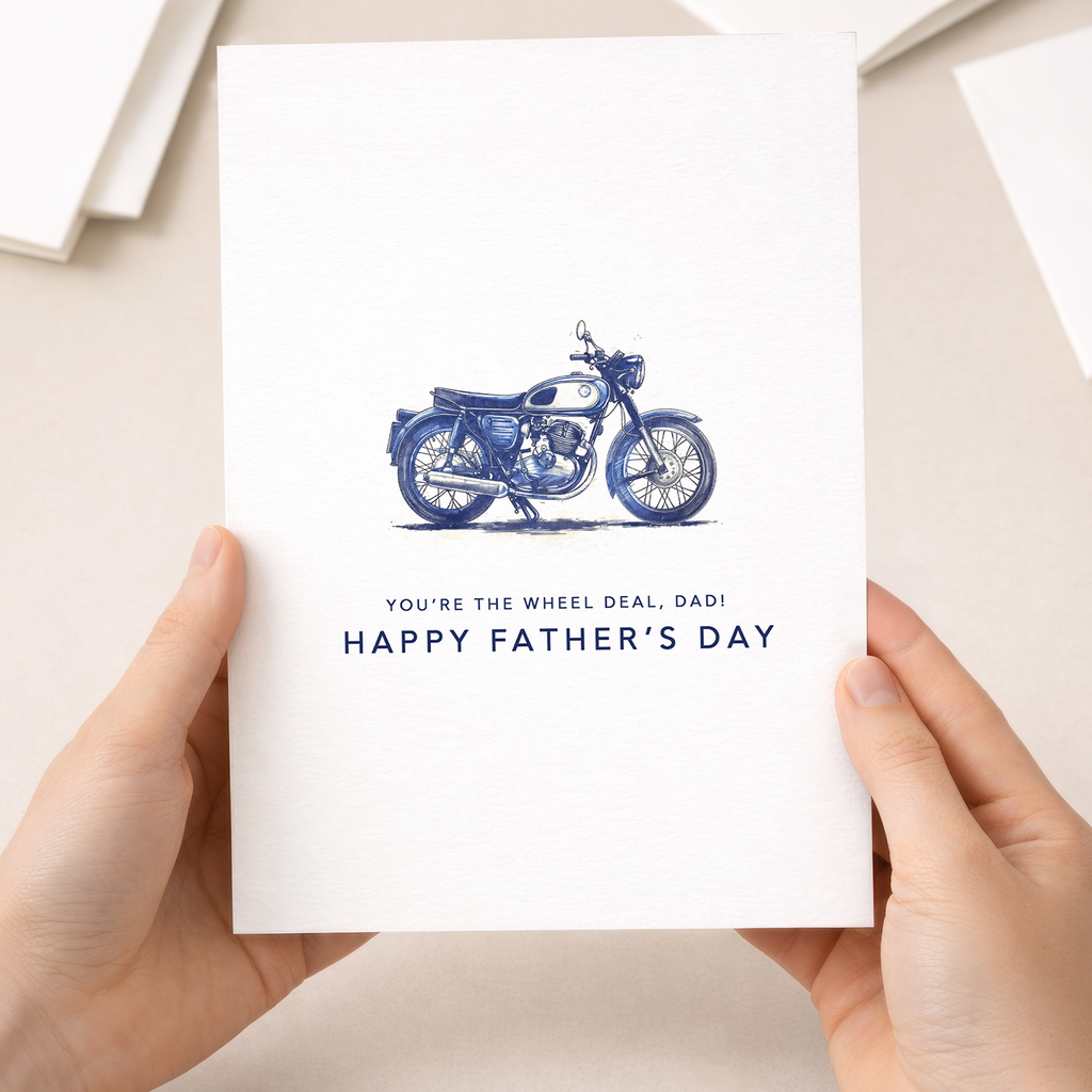 A simple and modern Father's Day greeting card for motorcycle enthusiasts featuring a minimalist blue motorbike illustration and the punny text You're the Wheel Deal Dad on a white background.
