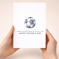 Minimalist Father's Day greeting card featuring a blue and white football with the text "On the ball Dad" on a white background.