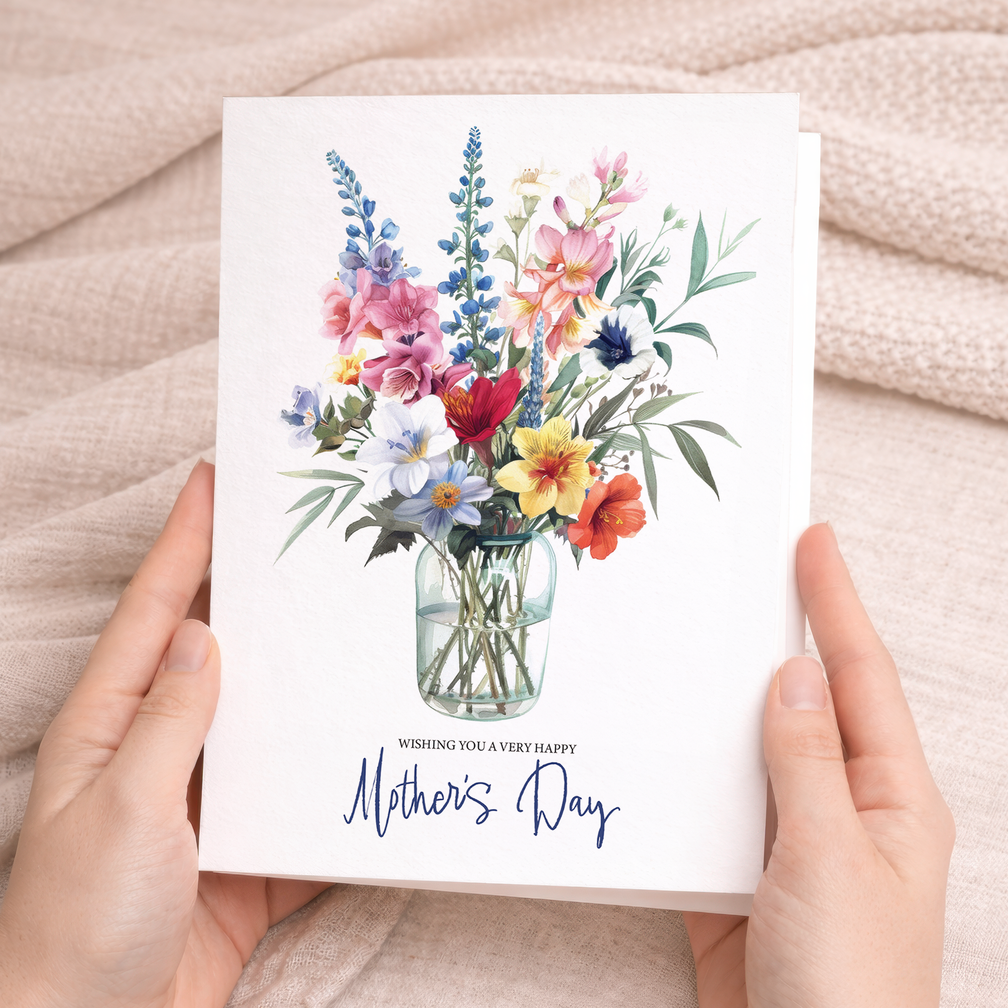 A vibrant Mother's Day greeting card featuring a colorful arrangement of mixed floral blooms and green leaves on a clean white background.
