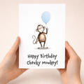Cute monkey birthday card for children featuring an illustration of a cheeky brown monkey and a colorful party hat.