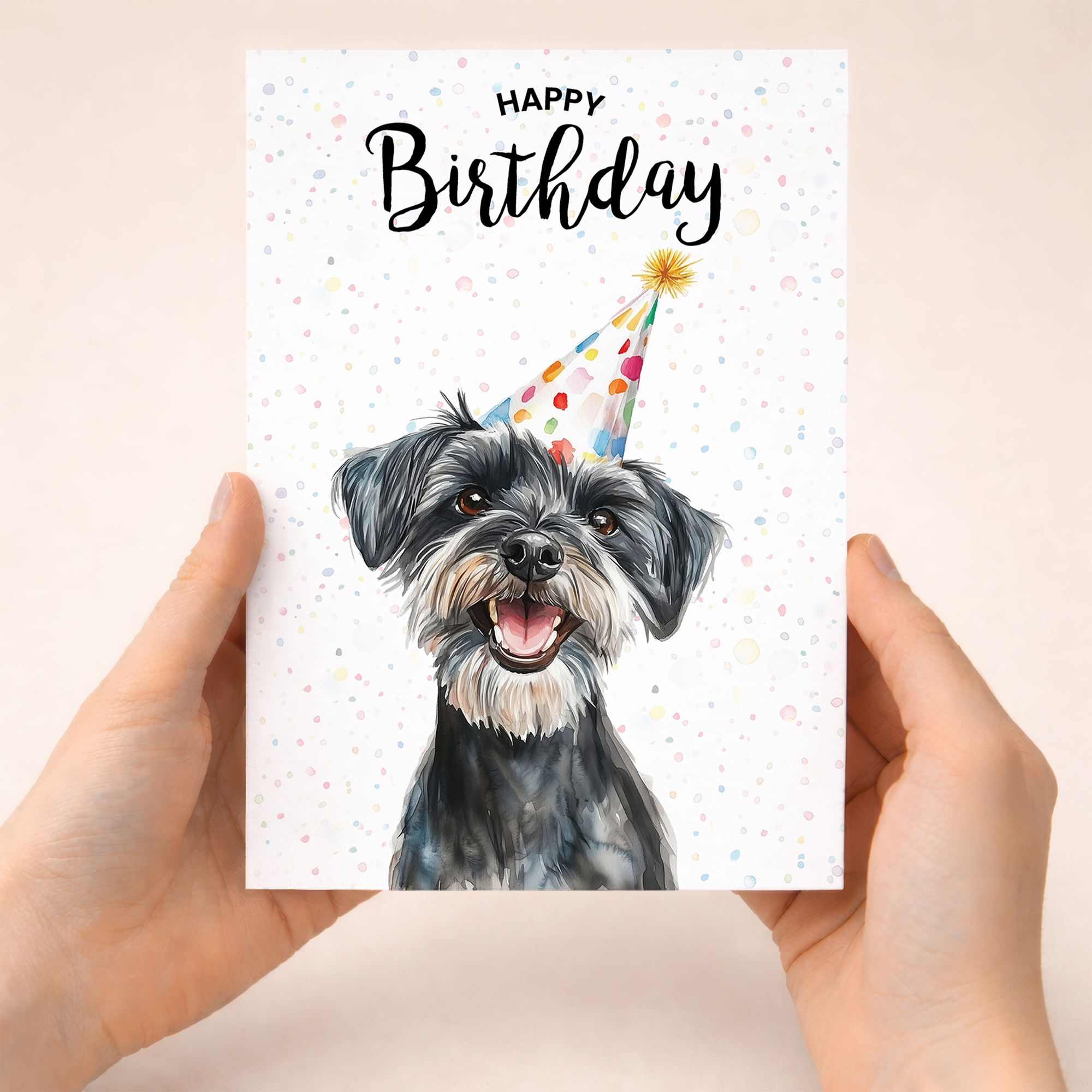 A watercolour illustration of a Schnauzer dog with a celebratory party hat on a white birthday greeting card.