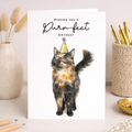 A birthday greeting card featuring an illustration of a cute tortoiseshell cat wearing a colorful party hat.