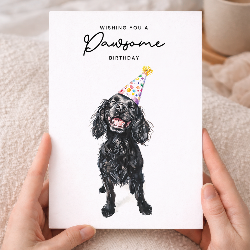 A portrait-oriented greeting card featuring an illustration of a Cocker Spaniel wearing a colorful party hat with the caption Wishing You a Pawsome Birthday.