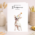 A cute Chihuahua wearing a colorful party hat on a birthday greeting card for dog lovers.